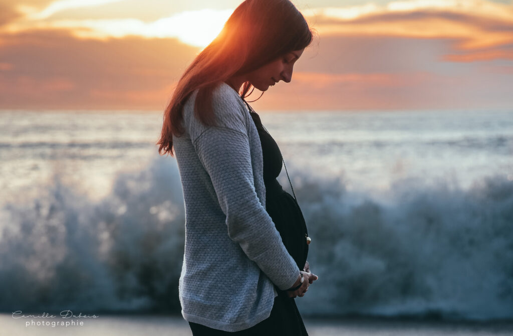 photographe de grossesse devant la mer avec coucher de soleil
