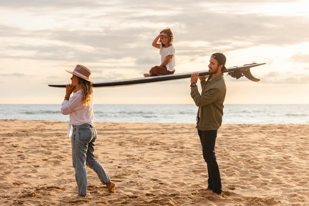 photo de famille sur la plage avec enfant sur un surf photo de famille en France par Camille Dubois Photographie